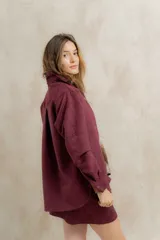 Falda corta de gamuza color bordó, con detalle de bordado geométrico vertical en el frente y bolsillo decorativo lateral.