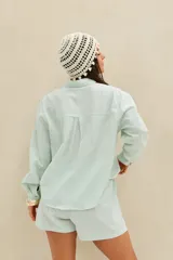 Camisa de rayas celestes y blancas, con cuello clásico, cierre frontal con botones y bolsillo ojal en el pecho.