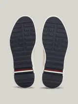 Zapatillas Tommy Hilfiger de cuero color blanco con detalles en azul marino. Presentan cordones azul marino, suela gruesa blanca y logo de la marca en el lateral.