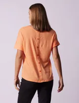 Remera blanca texturada con cuello redondo y mangas cortas con dobladillo. Detalle de botones en la espalda.