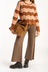 Sweater de tejido de punto con diseño de rayas horizontales onduladas en tonos marrón y beige. Presenta cuello redondo, mangas largas y corte oversize.