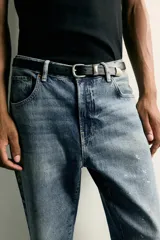 Jeans flare fit de hombre confeccionados en denim de algodón color azul con efecto lavado y roturas. Presentan diseño de cinco bolsillos, efecto salpicaduras de pintura en toda la prenda y bajo con acabado irregular.