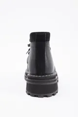 Borcego de cuero color gris con cordones color naranja, suela track negra de goma y detalle de gamuza en la parte superior del tobillo.