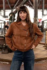 Chaqueta tipo biker de efecto gamuza en color marrón, con cierre frontal diagonal, solapas clásicas y bolsillos laterales con cierre metálico.