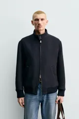 Cazadora de corte regular fit confeccionada en tejido de mezcla de lana y cashmere. Presenta cuello subido con cierre de botones, cierre frontal con cremallera de doble dirección, bolsillos laterales de vivo y acabados en rib de punto en puños y cintura.