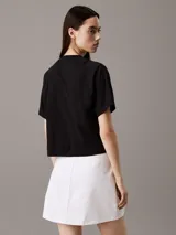 Remera negra de corte cropped y boxy, con cuello redondo y bolsillo en el pecho con bordado de escudo con logo.