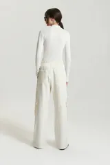 Pantalón babucha color crudo de gabardina con elástico en la cintura, cordón ajustable tipo zapatilla, bolsillos plaque y bolsillos cargo grandes en el delantero.