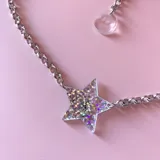 Collar plateado con cadena de eslabones y dije de estrella transparente relleno de glitter holográfico.