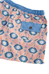 Short de baño rosado con estampado geométrico en azul y blanco, cintura elástica azul y cordón ajustable blanco.