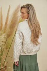 Campera corta color beige, con diseño acolchado de rombos, cuello tipo solapa y puños elásticos.