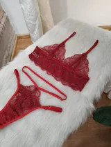 Conjunto de lencería de encaje color rojo, compuesto por un bralette triangular con breteles regulables y una tanga con tiras laterales ajustables.