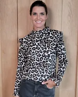 Polera de cuello alto con volados, manga larga y diseño con estampado animal print. Confeccionada en algodón.