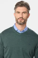 Suéter de tejido fino color azul marino, con cuello en V y manga larga. Presenta un pequeño logo bordado en el pecho.