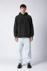 Buzo canguro de frisa gruesa con capucha, diseño oversize y acabado con efecto gastado. Presenta recortes horizontales en el frente y puños con elástico.