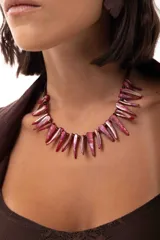 Collar corto compuesto por bastones de nácar teñidos en tonos fucsia y mostacillas oscuras. Cuenta con cierre de cadena de acero quirúrgico ajustable.