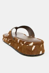 Sandalia plana tipo ojota con plataforma baja, confeccionada en piel con estampado animal print tipo ciervo en tonos marrones y blancos. Tiras separadoras de dedos forradas en el mismo material y suela con base dentada.