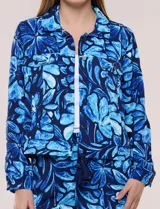 Camperita liviana de silueta entallada, con estampado floral en tonos azules, cuello camisero, cierre frontal con botones y bolsillos en el pecho.
