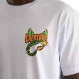 Remera blanca de manga corta con cuello redondo, confeccionada en algodón. Presenta un estampado gráfico pequeño en el pecho con el logo de la marca Creature y una cadena con una bomba.