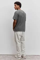 Remera de algodón color marrón con efecto lavado, de corte clásico y cuello redondo. Presenta un pequeño bordado de un pájaro en el pecho.