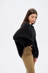 Sweater de punto negro, con cuello redondo a la base, manga larga y diseño holgado.