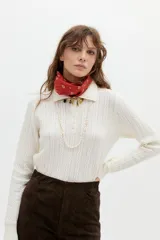 Sweater tipo polo color blanco roto, tejido en ochos, con cuello clásico y media cartera de botones.