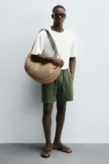 Bolso de hombro negro con acabado trenzado. Tiene un compartimento principal con cierre de cremallera y un bolsillo plano en el interior. El asa de hombro es ajustable.