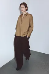 Camisa de corte amplio confeccionada en algodón, con cuello solapa, manga larga con puños y cierre frontal con botones ocultos bajo solapa. Presenta un bolsillo frontal en el pecho.