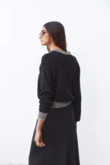 Campera bomber negra de tejido de punto con cuello, puños y ruedo acanalados con rayas blancas.