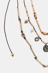 Pack de tres collares de diferentes largos, compuestos por cordones oscuros, piezas metálicas labradas, abalorios de colores, perlas y diversos charms colgantes con aplicaciones de cristales y brillos.