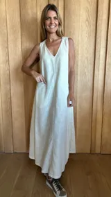 Vestido largo de lino color beige, sin mangas, con escote en V, bolsillos laterales y tajos en los laterales del ruedo.