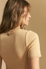 Remera de manga corta en tejido acanalado, con escote en V y detalles de puntilla en el borde del escote y en las mangas. Presenta un ajuste entallado al cuerpo.