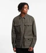 Campera masculina color verde oliva, estilo parka, confeccionada en sarga de algodón. Cuenta con cuello con solapa, cierre con botones, manga larga y múltiples bolsillos táticos delanteros.
