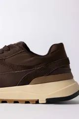 Championes urbanos de diseño técnico, combinando paneles de gamuza y tela técnica en tonos marrones. Presenta una entresuela de plataforma en color crema con suela dentada de goma.