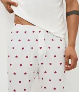 Pijama largo para hombre compuesto por una remera de manga corta blanca con cuello redondo bordó y estampa frontal de dados con la leyenda 'Lucky to Have You', y un pantalón largo blanco con estampado full print de corazones bordós y cintura elástica.
