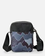 Morral Rip Curl modelo No Idea Pouch Search Camo, confeccionado en poliéster con diseño estampado de montañas y tecnología Hydroprotech. Cuenta con correa ajustable para el hombro y múltiples compartimentos con cierre.