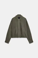 Chaqueta estilo bomber de color verde militar, confeccionada en tejido de efecto gamuza. Presenta cuello solapa, cierre frontal con cremallera metálica, bolsillos delanteros de vivo y bajo con acabado elástico.