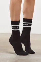 Medias altas de algodón color negro, con diseño acanalado y dos franjas blancas horizontales en la parte superior. Incluyen el logo Basset bordado en blanco.