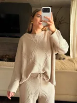 Sweater de tejido de punto color beige con diseño de rombos geométricos. Presenta silueta amplia, cuello redondo y mangas largas con caída suave.