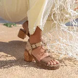 Sandalia de cuero vacuno color marrón con tira ancha en la parte delantera, tira ajustable al tobillo color tostado con hebilla metálica y taco cuadrado de madera.