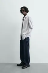 Camisa slim fit blanca de manga larga, cuello italiano y puños con botón. Cierre frontal de botonadura.