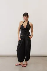 Pantalón holgado negro tipo bombacho, con cintura elástica y puños fruncidos en los tobillos.