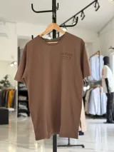 Remera oversize color beige, con diseño estampado en la espalda que incluye tipografía grande y texto descriptivo en negro.