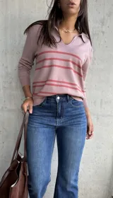 Sweater de tejido fino en color rosa, con diseño de rayas horizontales en tono más oscuro. Presenta cuello tipo polo con escote en V y mangas largas con puños ajustados.