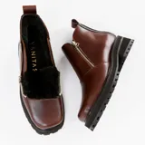 Bota de cuero vacuno color marrón, con interior forrado en corderito natural. Tiene suela de goma artesanal, punta cuadrada, cierre YKK en ambos lados y caña de 11cm.