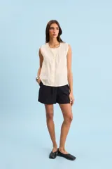 Blusa sin mangas de algodón color crudo, con cuello redondo, corte relajado y detalles de costuras y pespuntes en contraste.