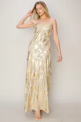 Vestido largo de tirantes finos con escote en V, confeccionado en tela fluida con estampado metalizado en tonos dorados y plateados. Presenta un diseño de corte recto y espalda descubierta.