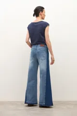 Jean wide leg bicolor en tonos de gris oscuro, con paneles laterales más oscuros y ruedo deshilachado.