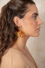 Caravanas colgantes con diseño floral, formadas por una argolla dorada y un dije de pétalos de resina con detalle de perla central.