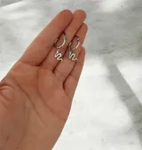 Aros tipo argolla pequeña con dije colgante en forma de serpiente, fabricados en acero quirúrgico.