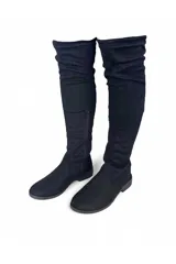 Bota bucanera de gamuza marrón, de caña alta elástica por encima de la rodilla, punta redondeada, suela plana y cierre lateral interno.